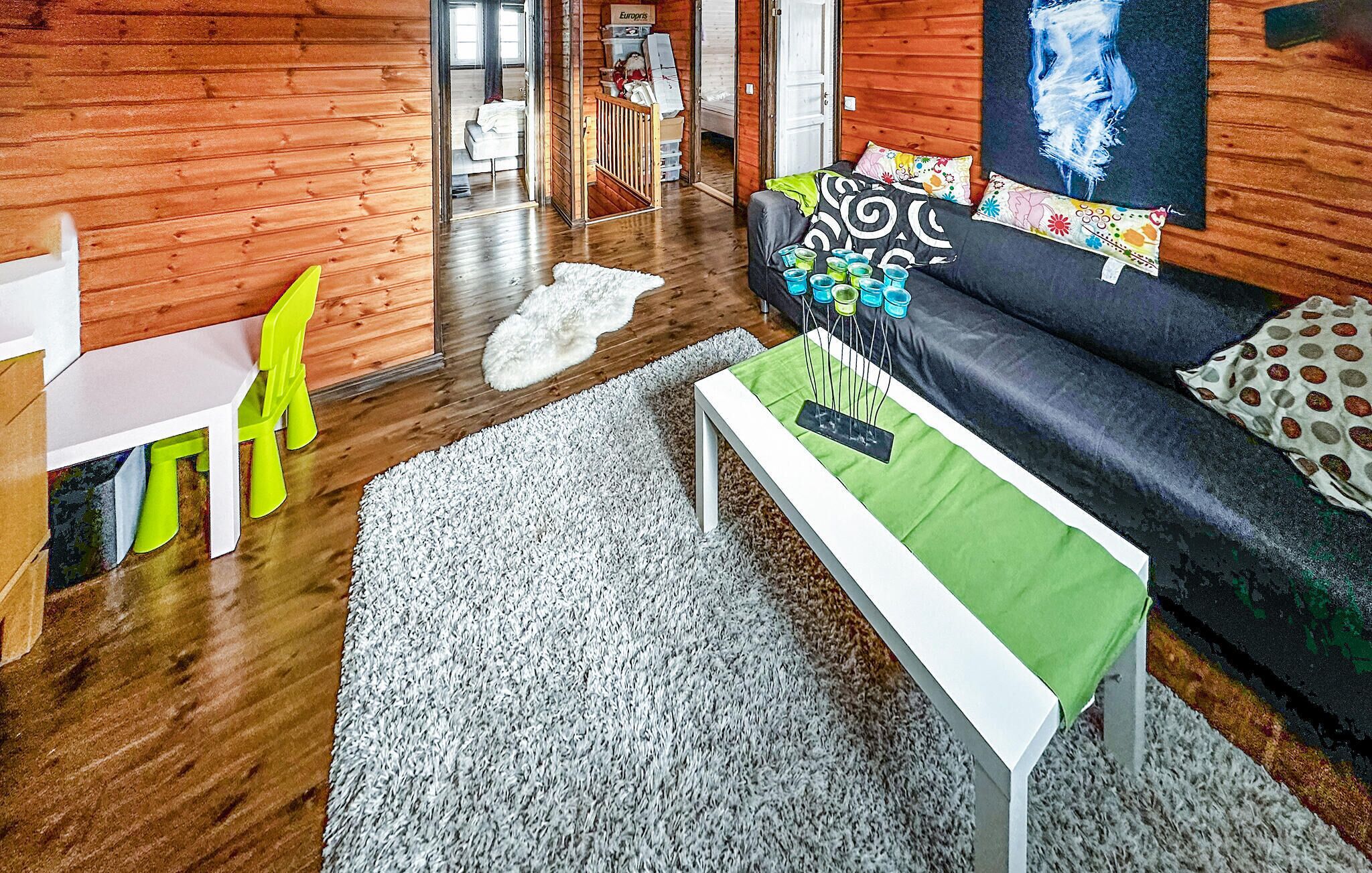 A modern living room with wooden walls, a black sofa with colorful cushions, a white bench, and a bright yellow chair.