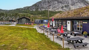 A rustic outdoor seating area with picnic tables and a small building labeled 'KAFE'. - 4 bedroom awesome home in Rysstad (Rysstad)