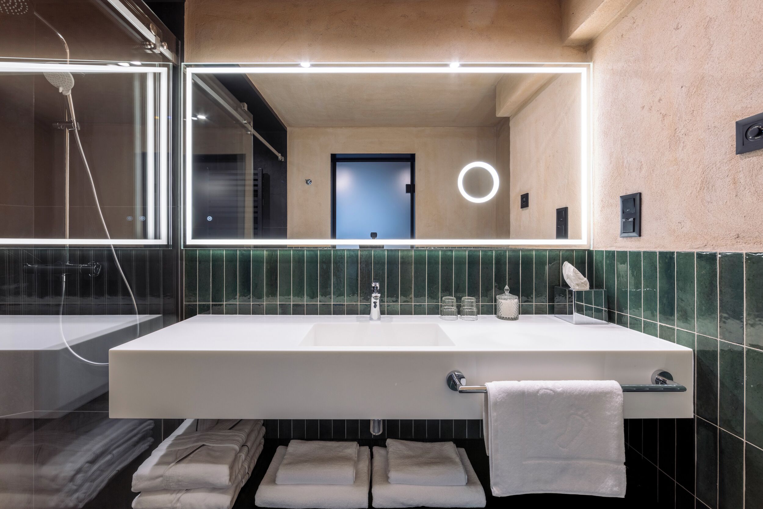 A modern bathroom with a large mirror, a white sink, and a glass shower enclosure.