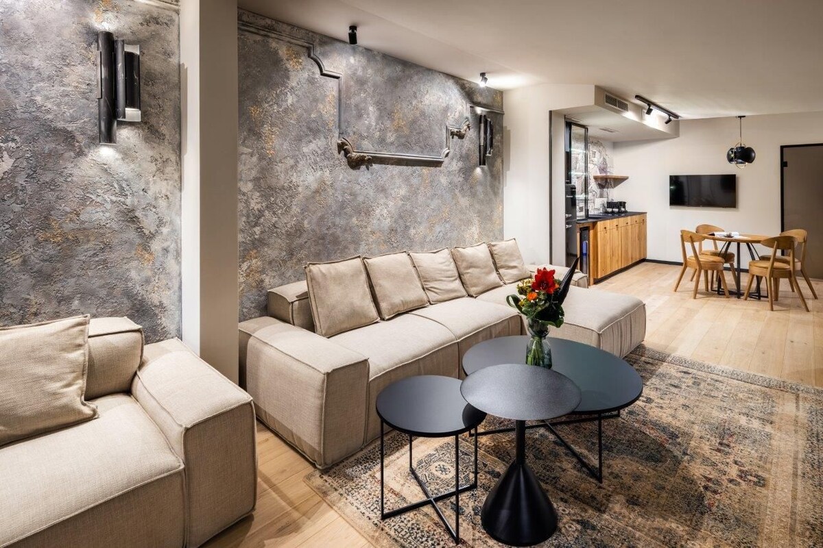 A modern living room with a sectional sofa, a coffee table, and a dining area with wooden chairs.