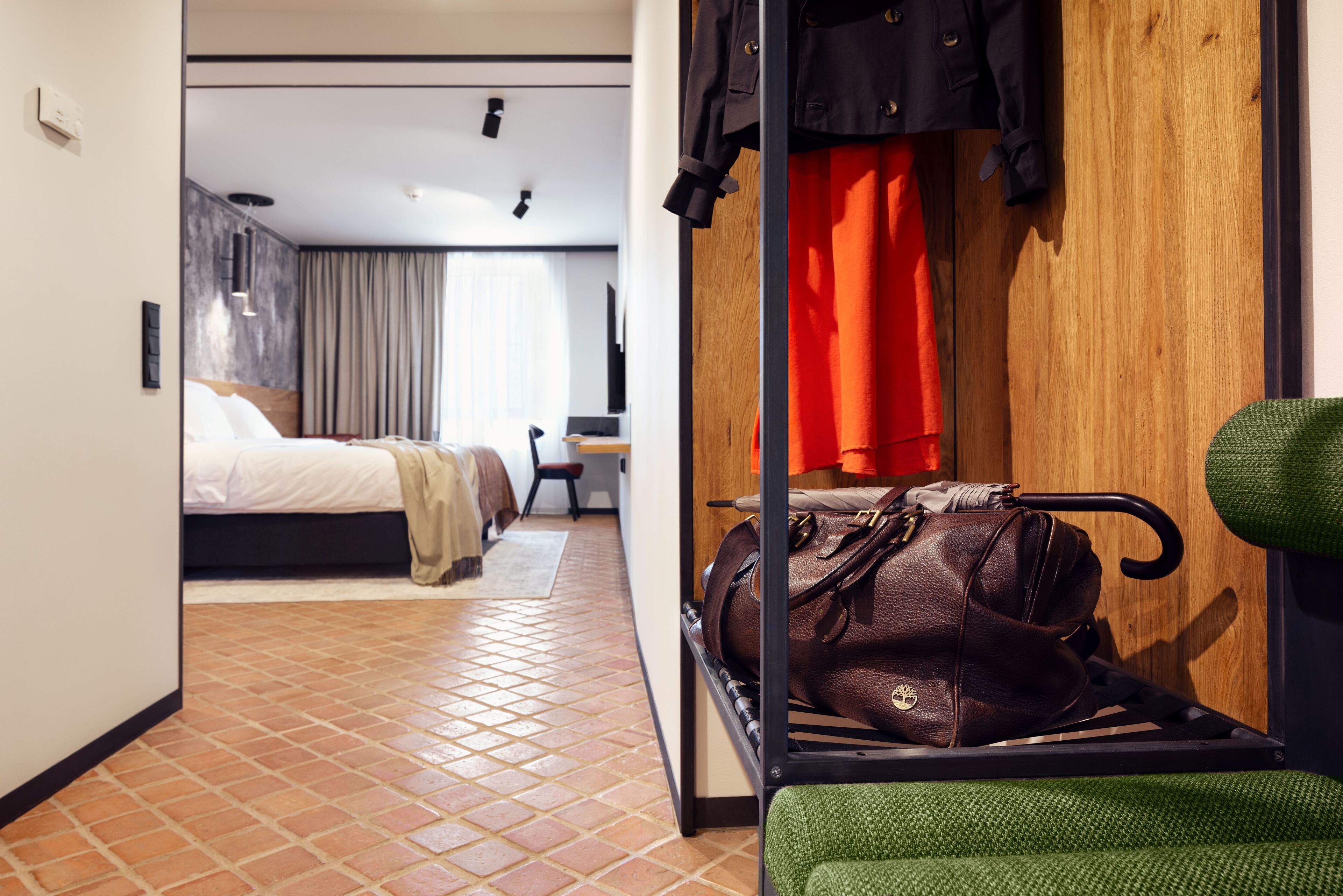 A hotel room with a bed, a desk, a chair, a luggage rack, and a wardrobe.