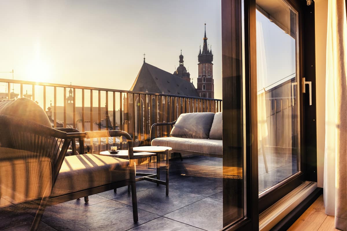Ein Balkon mit einer Couch, einem Sessel und einem Tisch, mit Blick auf ein Gebäude mit einem Turm.