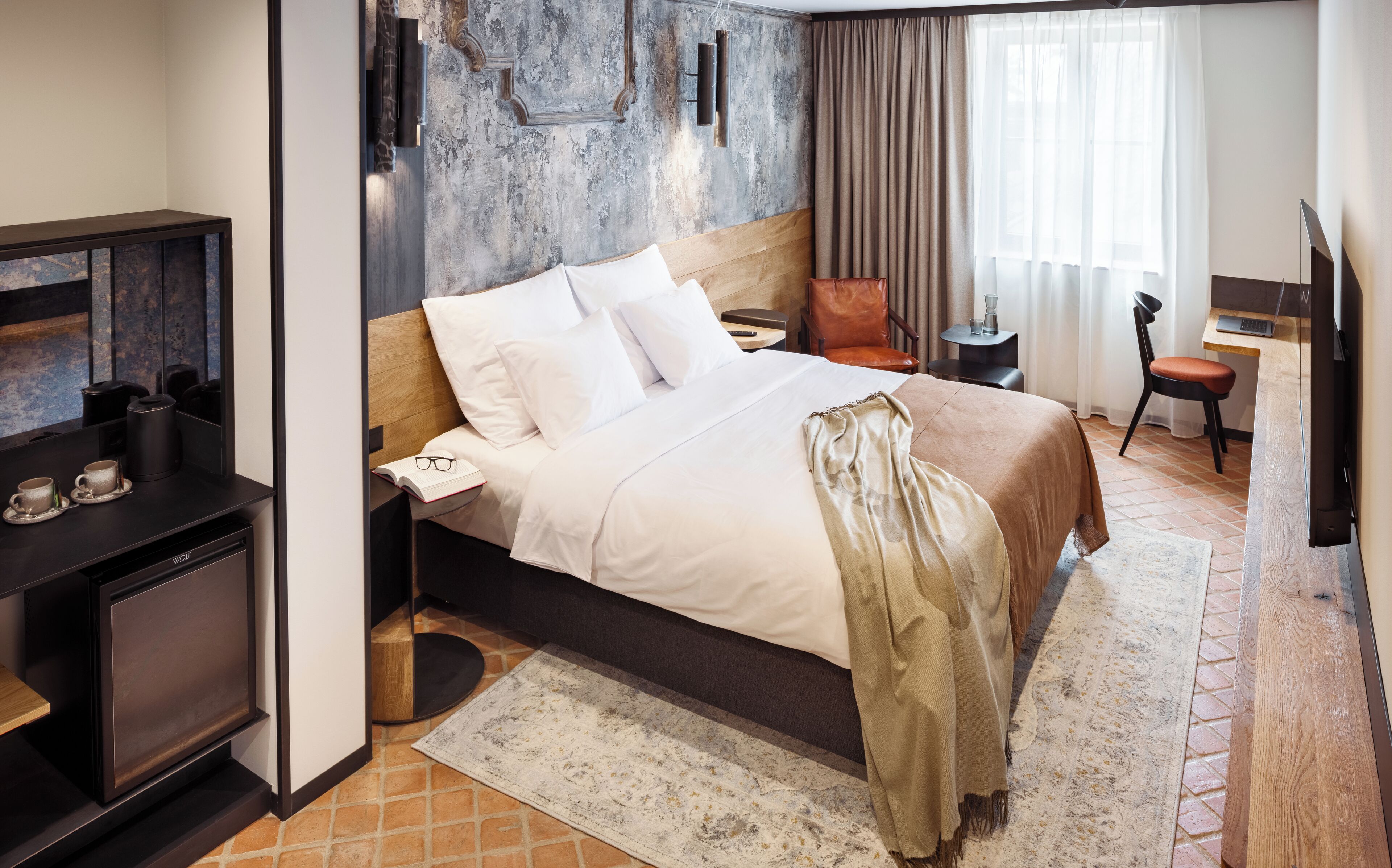 Une chambre d’hôtel équipée d’un lit, d’un bureau, d’une chaise, d’une machine à café et d’une télévision.