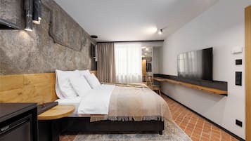 Un dormitorio moderno con cama, mesita de noche, televisión y un espejo grande.
