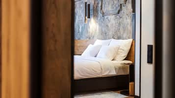A modern bedroom with a wooden headboard, a bed with white linens, and a textured wall behind it.