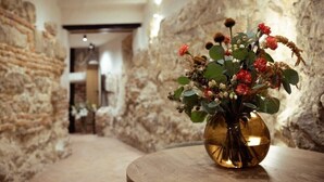 A narrow stone corridor with a round wooden table holding a vase with flowers. - Nomadic Urban Premium Suites (Kraków)