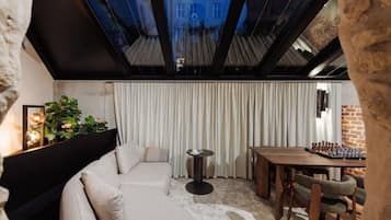 Een moderne kamer met een bank, een klein rond tafeltje, een eettafel met stoelen en uitzicht door een dakraam.