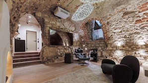A rustic interior with stone walls, a wooden staircase, a modern sofa, and a projector. - Nomadic Urban Premium Suites (Kraków)