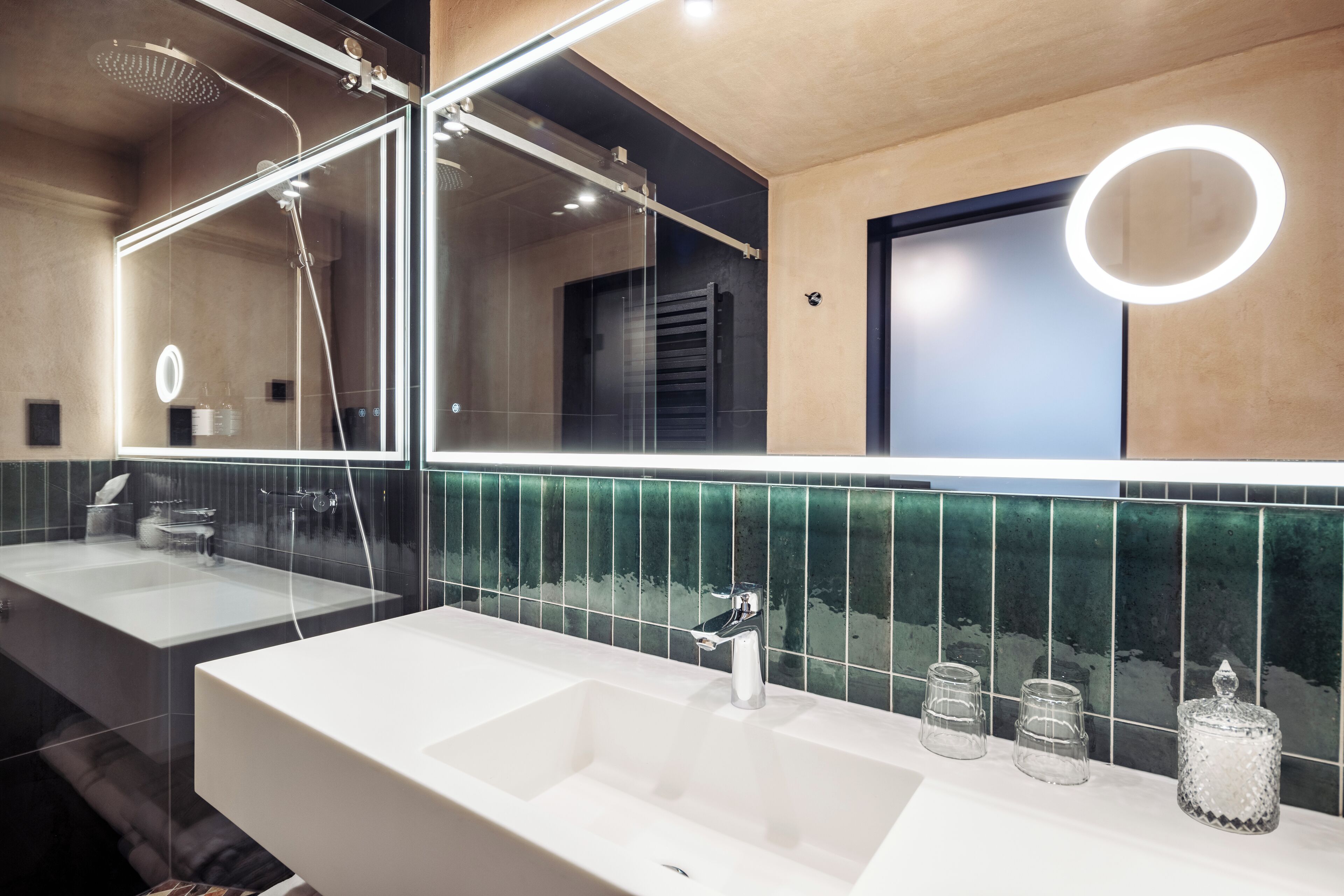 Un baño moderno con un espejo grande, una ducha y un lavamanos blanco.