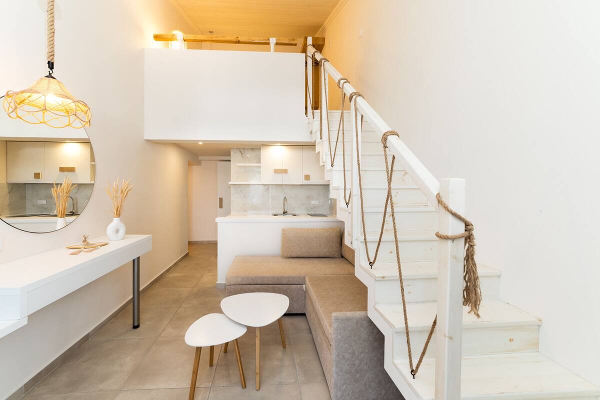 A modern, minimalist interior with a staircase, white walls, and a seating area.