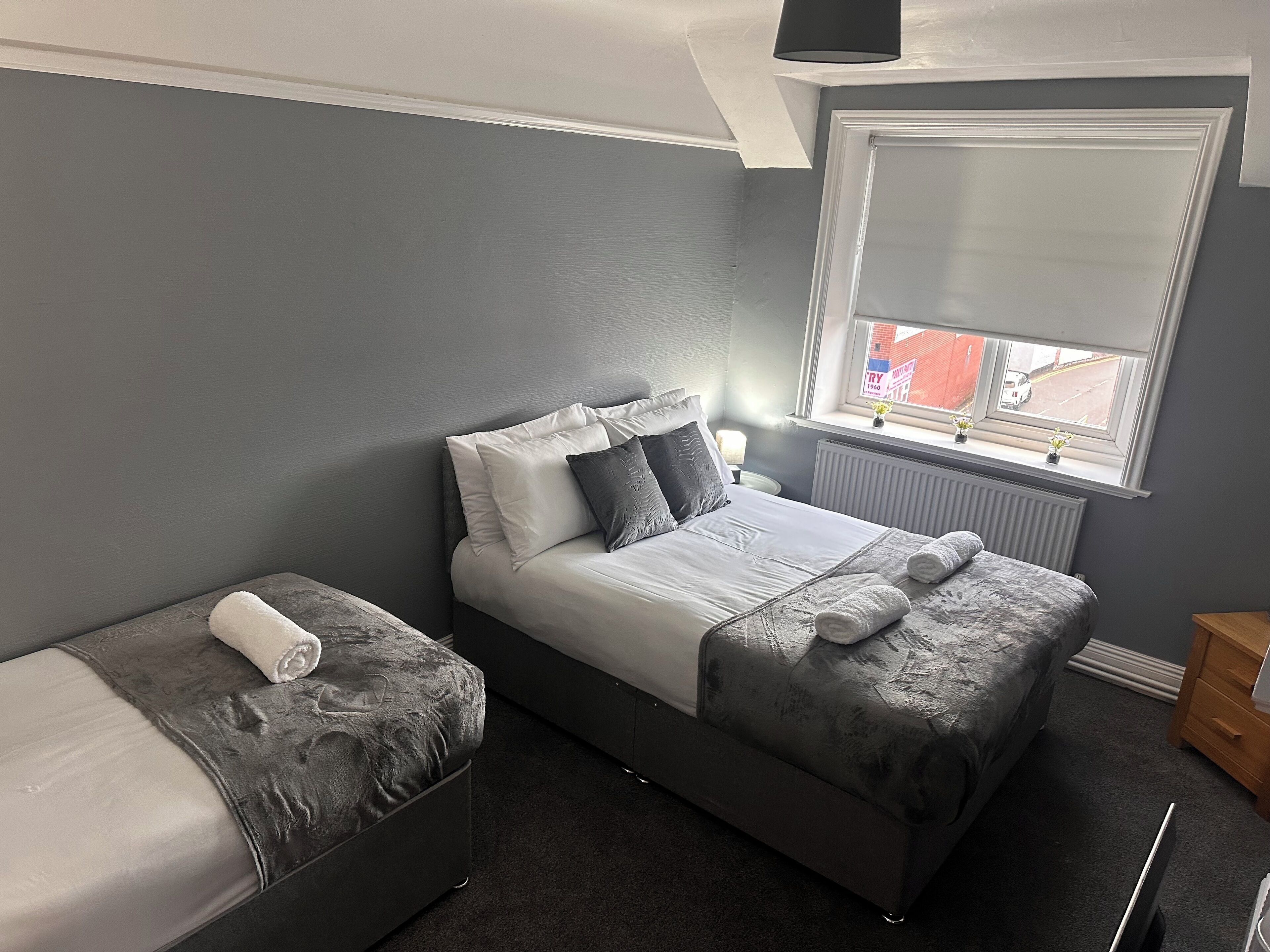 A bedroom with a bed, a small sofa, and a window with blinds.