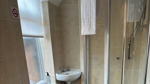 A modern bathroom with a toilet, sink, shower, and a small window. - Sheridans (Wallasey)