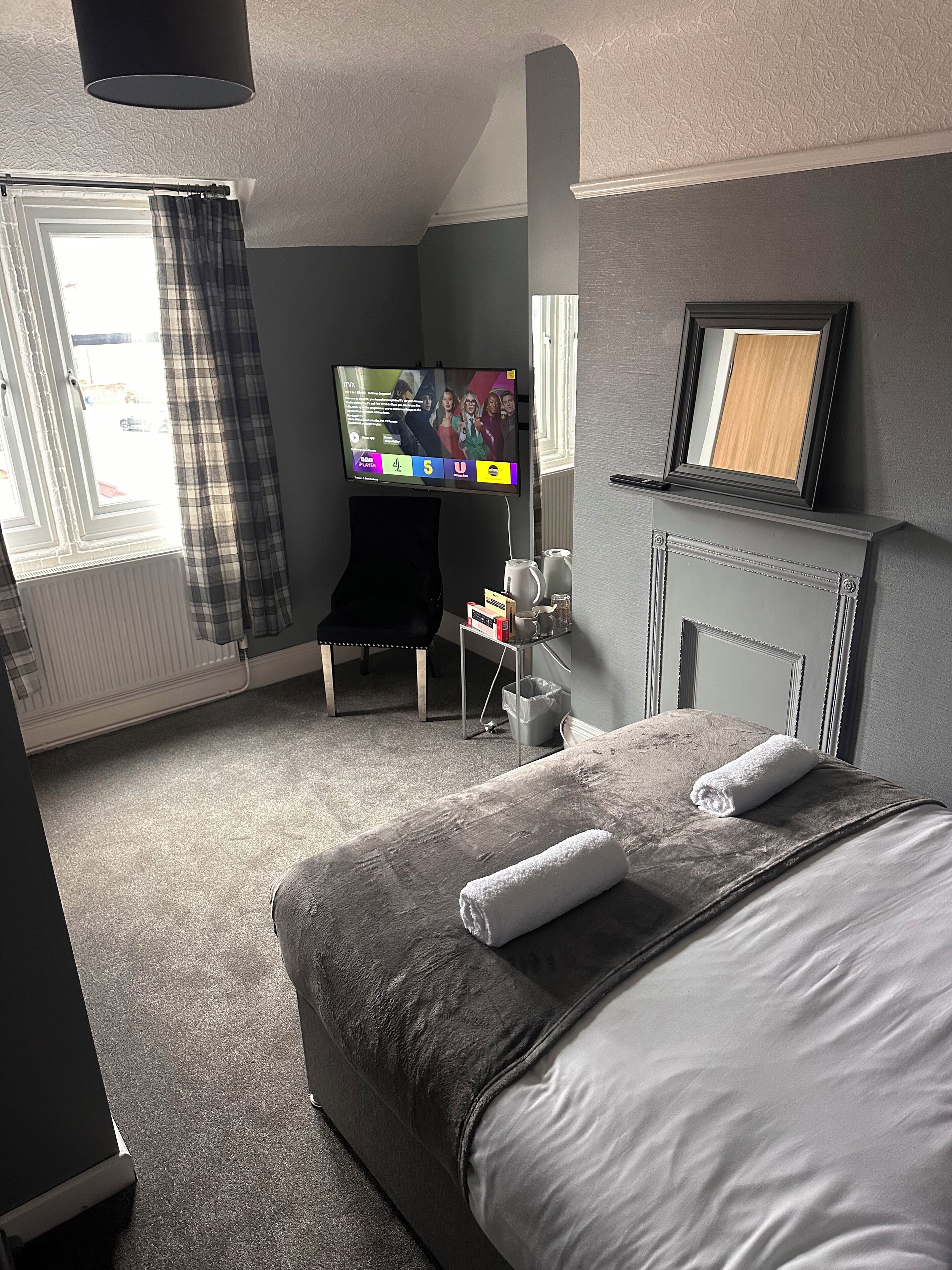 Een hotelkamer met een bed, een televisie, een tafeltje en een raam met gordijnen.