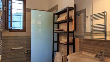 Un baño moderno con inodoro, lavamanos y estantes empotrados para toallas.