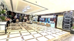 Un espace d’accueil d’hôtel comprenant un comptoir d’enregistrement, un coin salon et un bureau de réception.