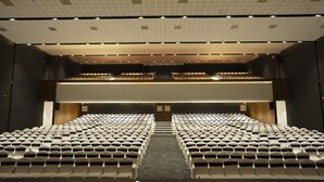 Un théâtre avec des rangées de sièges, une scène à l’avant et un plafond doté d’un éclairage encastré.