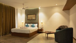 Une chambre d’hôtel avec un lit, une chaise, une table de chevet et un ventilateur de plafond.