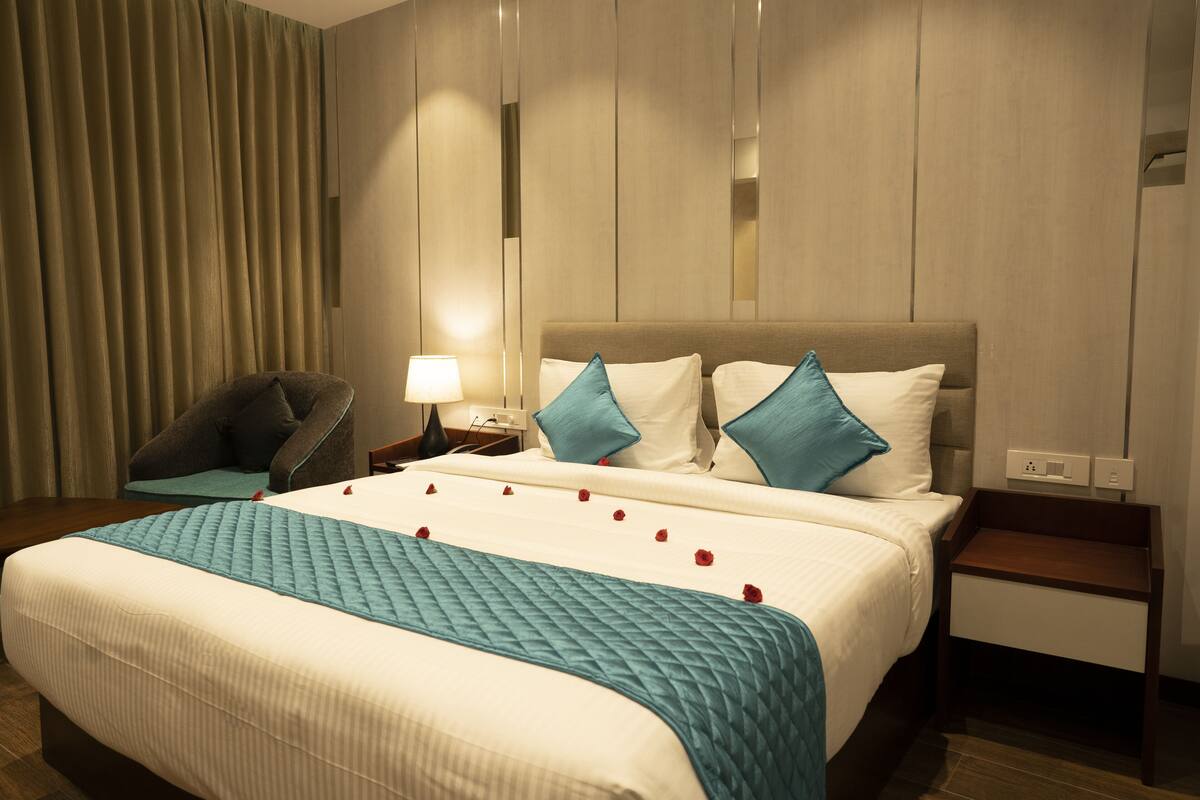 Une chambre d’hôtel avec un grand lit, une table de chevet, une chaise et une lampe.