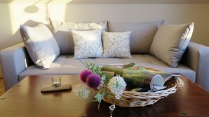 A living room with a sofa, two patterned pillows, a wooden coffee table, and a wicker basket with flowers. - Unsere Casita- Idylle in Ruhe und mit Kleinem Beach (Apensen)