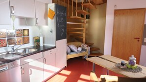 A compact kitchen with a sink, a refrigerator, and a dining area with a table. - Unsere Casita- Idylle in Ruhe und mit Kleinem Beach (Apensen)