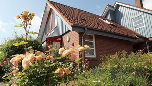 A two-story house with a red-tiled roof, a brick facade, and a red-framed window. - Unsere Casita- Idylle in Ruhe und mit Kleinem Beach (Apensen)