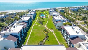 A resort with a central pool, multiple buildings, and a beach view. - Loggerhead 424 2 Bedroom Condo by RedAwning (Sanibel)
