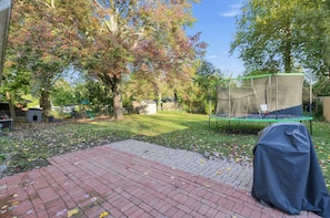 A backyard with a trampoline, a covered play area, and a brick patio. - Damaged Shower (Kalamazoo)
