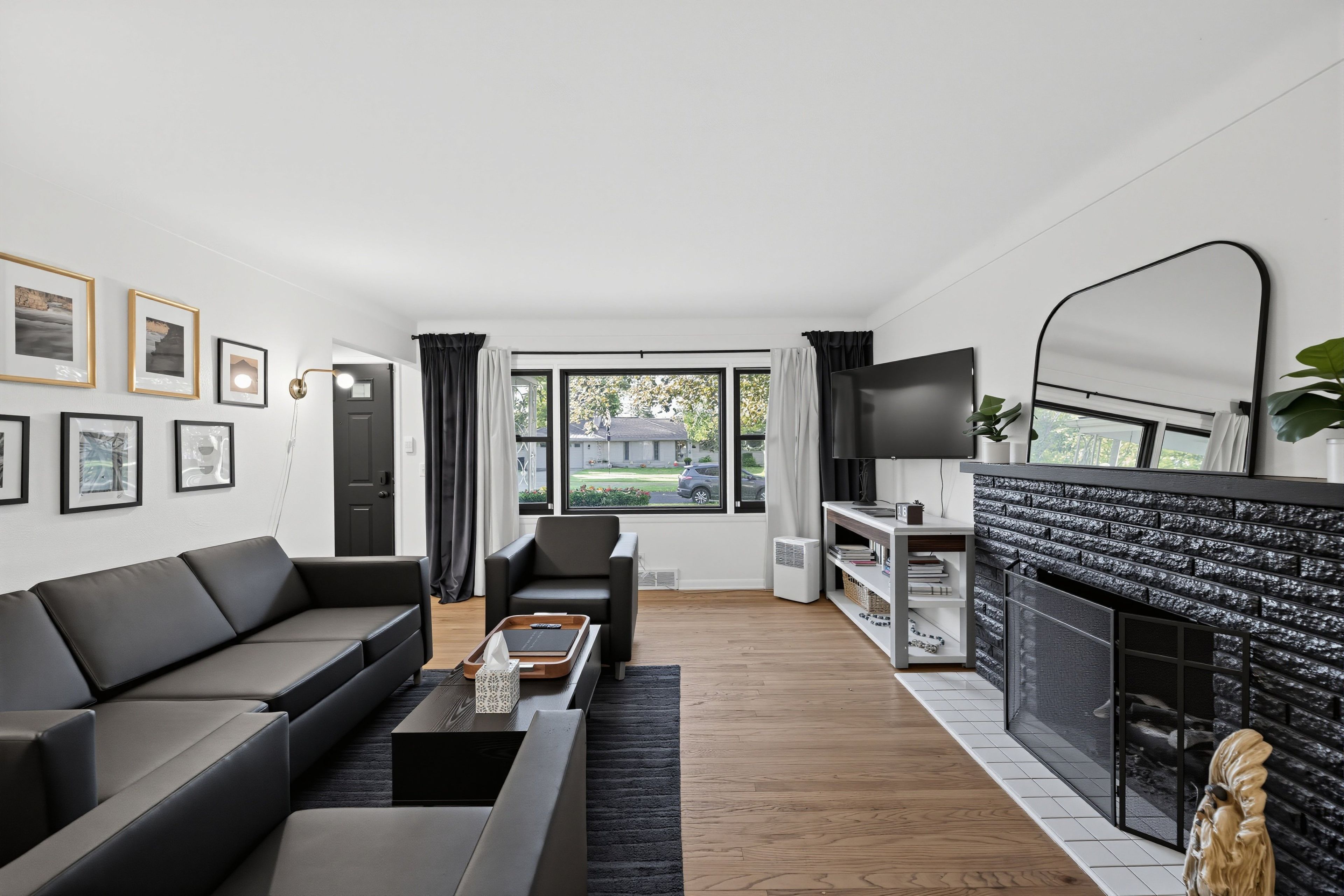 A modern living room with a black sofa, a coffee table, a fireplace, and a TV.