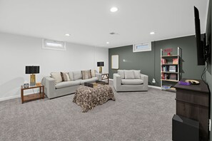 A living room with a sofa, armchair, coffee table, and a bookshelf. - Damaged Shower (Kalamazoo)