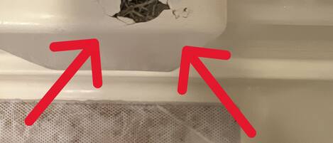 A white bathtub with a hole in the back wall and a mesh drain cover.