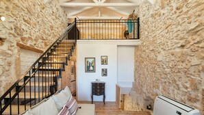 A cozy interior with a stone wall, a staircase, a sofa, and a small table with candles. - Beit Petra Chania (Chania)