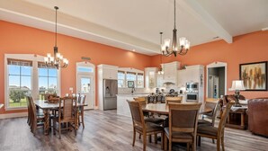 A spacious kitchen with white cabinets, a dining area with wooden chairs, and a large window offering a view of the outdoors.
