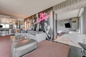 Un salon moderne avec une grande fresque murale, un canapé, une table basse et une baignoire.