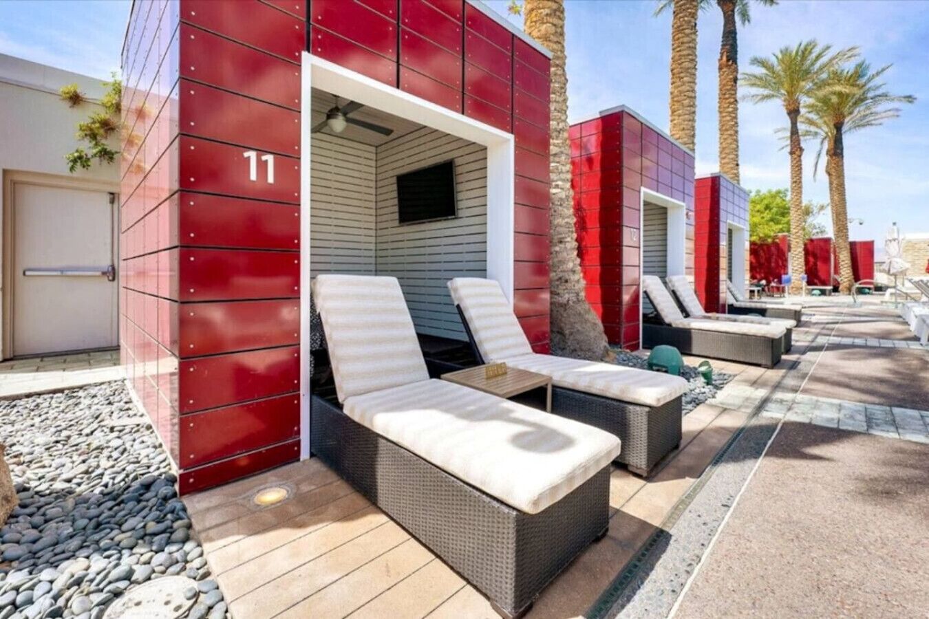 A modern outdoor lounge area with red walls, numbered room 11, and multiple seating options.