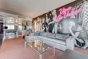 Un hall d’hôtel moderne, agrémenté d’une grande fresque murale, d’un espace détente avec un canapé et des fauteuils, et d’une table basse en verre.