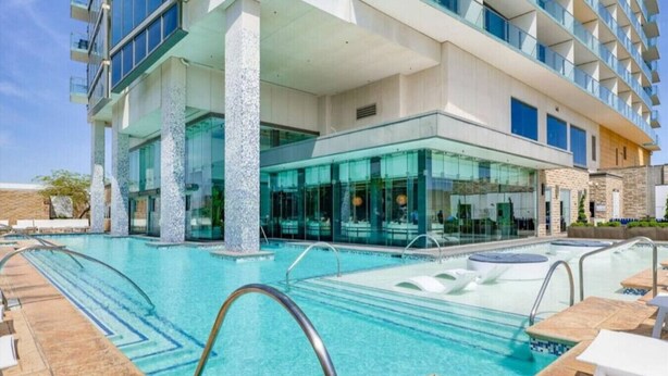 Et hotel med swimmingpool, udendørs siddepladser og moderne arkitektur.