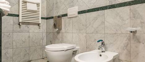 Un baño con inodoro, bidé y toallero.