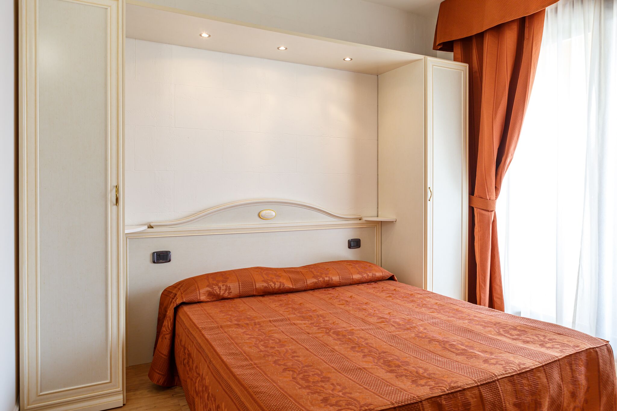 Une chambre à coucher avec un lit, une armoire et une fenêtre avec des rideaux.