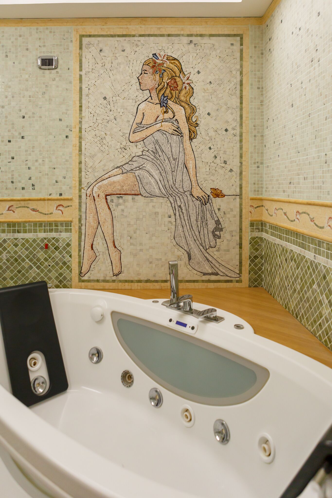 A bathroom with a mosaic wall, a bathtub, and a sink.