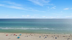 A beach with clear skies, calm waters, and several beach umbrellas and sun loungers. - FREE Beach Service, Golf + Perks! Emerald Beach 1430 Pool, Hot Tub &Starbucks (Panama City Beach)