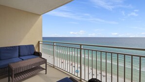 A balcony with a wicker sofa and a view of the beach and ocean. - FREE Beach Service, Golf + Perks! Emerald Beach 1430 Pool, Hot Tub &Starbucks (Panama City Beach)