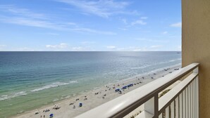 A beach view from a balcony with a railing, clear sky, and calm sea. - FREE Beach Service, Golf + Perks! Emerald Beach 1430 Pool, Hot Tub &Starbucks (Panama City Beach)