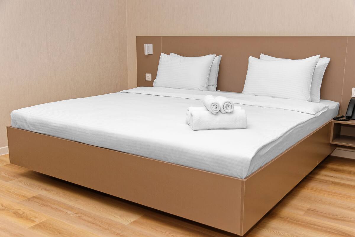 A modern hotel room with a large bed, white linens, and neatly folded towels.