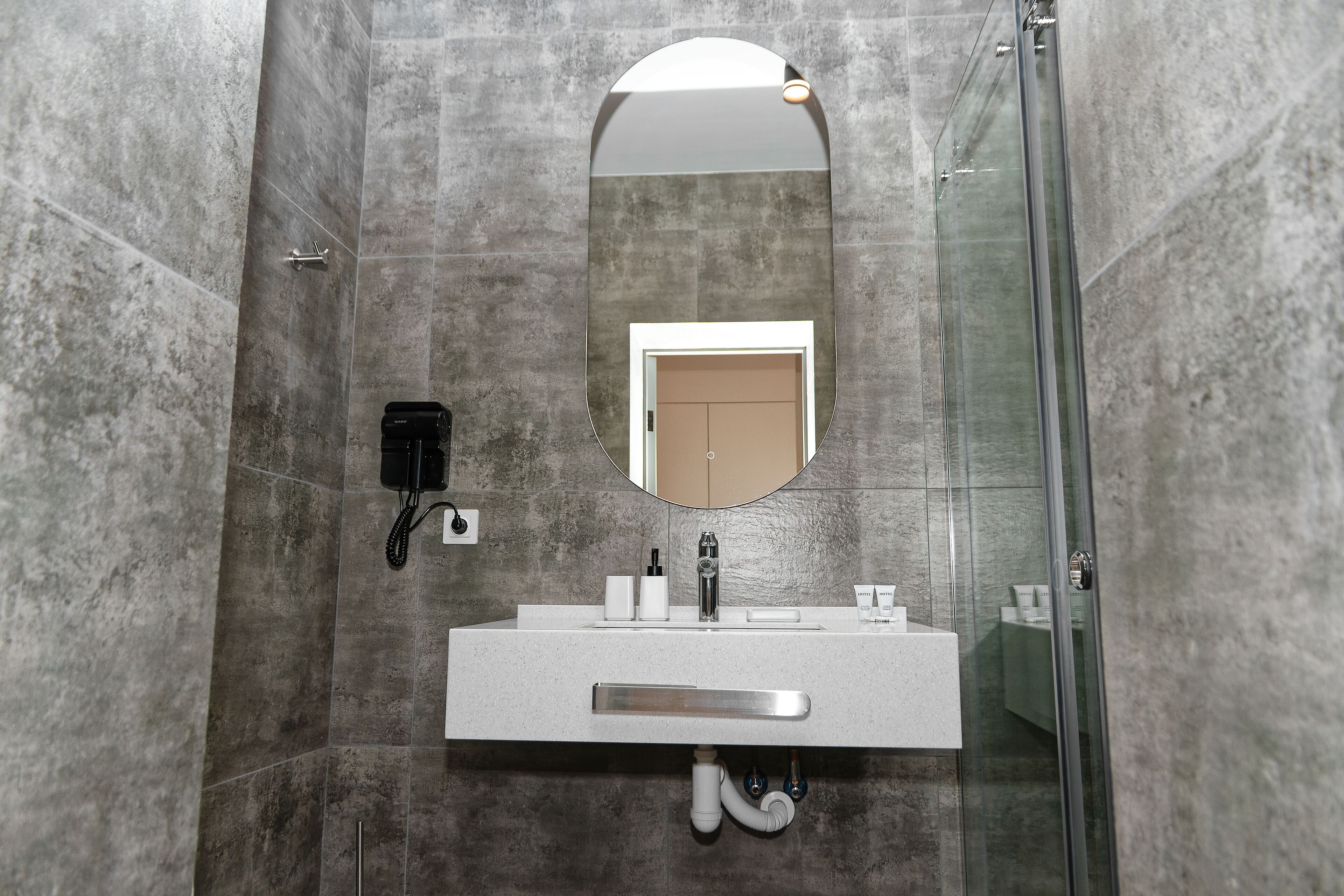 A modern bathroom with a large mirror, a sink with toiletries, and a shower area.