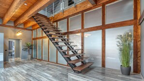 Ein modernes Interieur mit einer Holztreppe, großen Fenstern und einem Blumentopf.