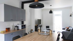 Eine moderne Küche mit grauen Schränken, einem Holztisch und Pendelleuchten.
