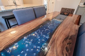 A dining table with a glass top featuring a blue resin design with embedded stones.