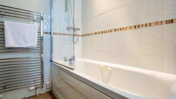 A modern bathroom with a glass-enclosed shower, a white bathtub, and a towel rack with a white towel.