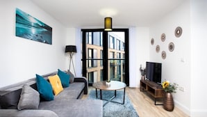 A modern living room with a grey sofa, a round coffee table, and a TV stand. - Absolute Stays on Essex-chinatown-hippodrome-alexandra Theatre-bull Ring-the Rep (Birmingham)