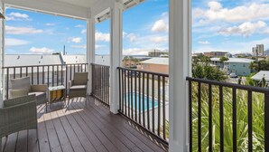 A covered outdoor area with a pool, wicker furniture, and a view of the surrounding neighborhood. - Salty Beach | Shared Pool + Easy Beach Access! (Panama City Beach)